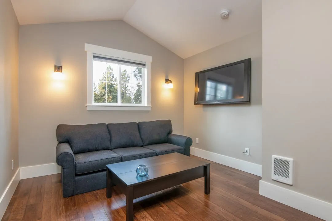 Gray 2 seat couch on brown wooden parquet flooring